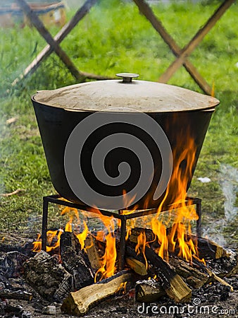 Food in a cauldron on a fire. Cooking outdoors in cast-iron cauldron. Stock Photo