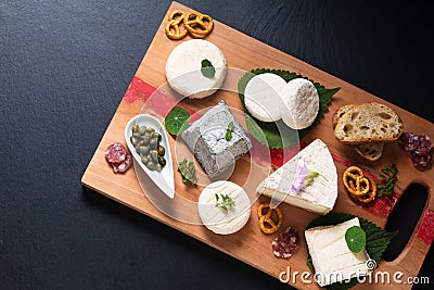 Food concept assortment French organic fresh goat cheese on wooden cheese board on black background with copy space Stock Photo