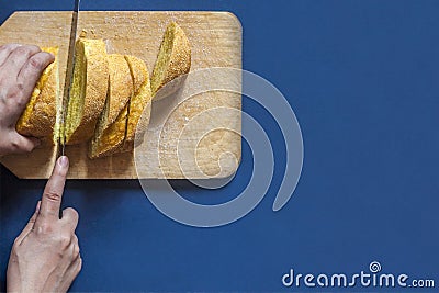 Food concept. Hand cutting bread. Slicing a bread. Top view Stock Photo