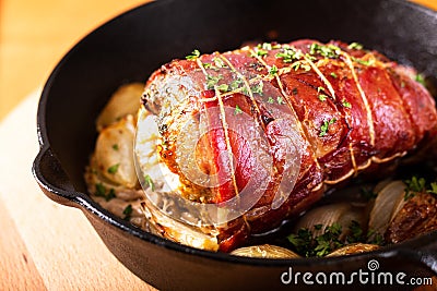 Food concept homemade Bacon Stuffed Pork Tenderloin baked in iron cast skillet on round wooden board Stock Photo