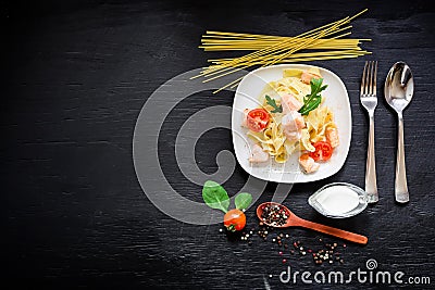 Food concept with tasty pasta with salmon and tomato on dark background. Flat lay, top view. Stock Photo