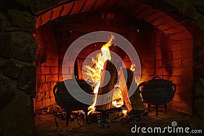 Food is cooked in the fireplace. Spread the fire. Bonfire and firewood. Fire. Cast iron casserole in the oven. Logs in Stock Photo