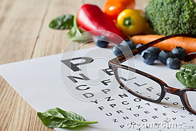 Food for eyes health, colorful vegetables and fruits, rich in lutein, eyeglasses and eye test chart on wooden background, concept Stock Photo