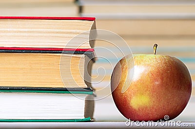 Food and knowledge of an apple, and next to a stack of hardcover books Stock Photo