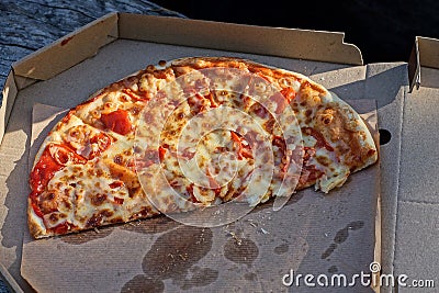 food from one piece of fried pizza lies on gray paper packaging box Stock Photo