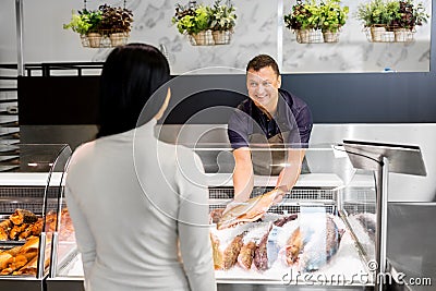 Seller showing seafood to customer at fish shop Stock Photo