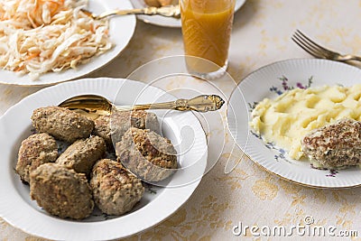 Food on the table, meat cutlets on a plate, steak with mashed potatoes, sauerkraut, glass of juice, spoon Stock Photo