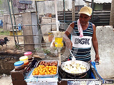 A food vendor cooks fish balls, sausages and quail eggs which he sells on a food cart Editorial Stock Photo