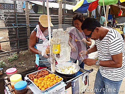 A food vendor cooks fish balls, sausages and quail eggs which he sells on a food cart Editorial Stock Photo