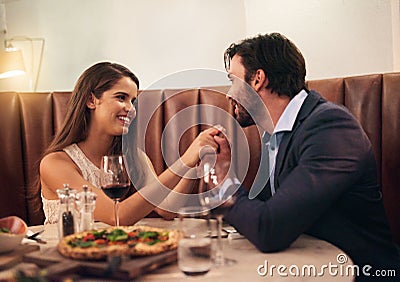 Food, wine and love, couple holding hands at table on valentines day date with smile, pizza and drinks. Date night, man Stock Photo