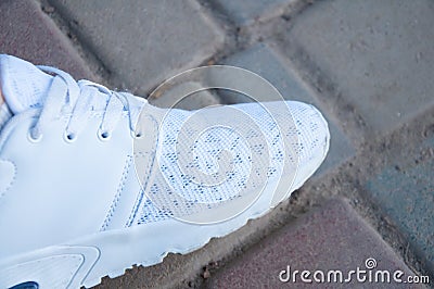 The foot of a man in white sneakers stands on stone steps in the summer. Walking in the shoes Stock Photo