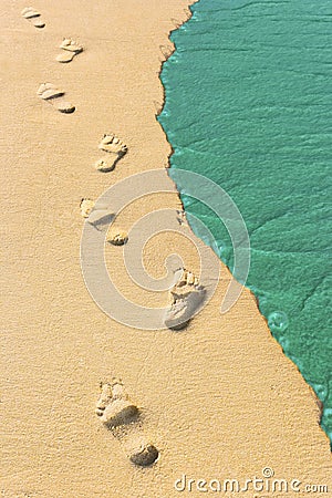 Foot steps and surf on tropical beach Stock Photo