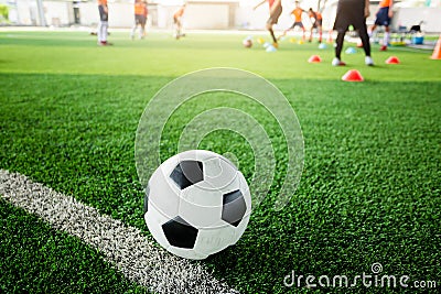 Football on green artificial turf with blurry soccer team training Stock Photo