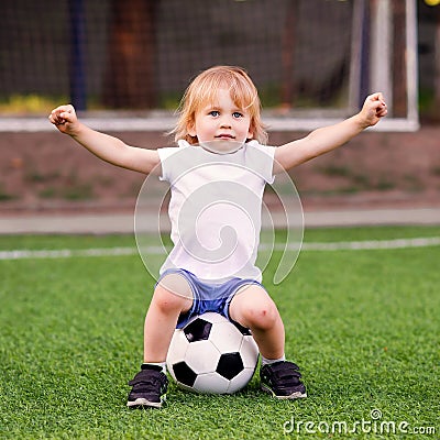 Football lesson in kindergarten preschool outdoors: little blonde goalkeeper protecting soccer goalposts with arms wide open Stock Photo