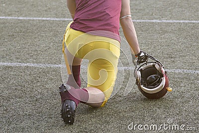 Football player kneeling and holding sport helmet on playing fie Stock Photo