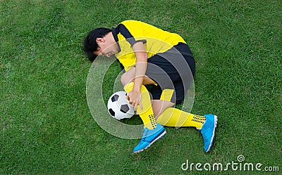 Football player in Yellow lying injured on the pitch. Stock Photo