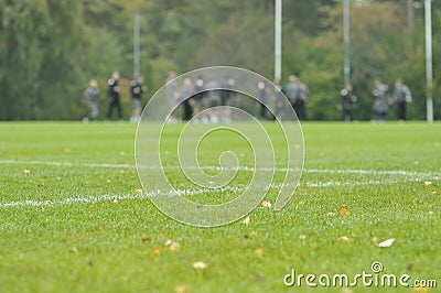 On a football practise and on a green field on a rainy, cold and grey Autumn afternoon with soccer players on a background Stock Photo