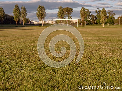 Football soccer field, Grass in focus, goal post out of focus, Cloudy sky Stock Photo