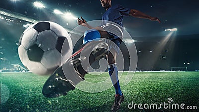 Football or soccer player in action on stadium with flashlights, kicking ball for winning goal, wide angle Stock Photo