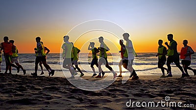 Football sport team is engaged in jogging training at sea at sunset Editorial Stock Photo