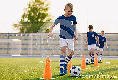 Footballer running with ball on training pitch. Soccer practice for junior level team Stock Photo