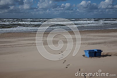 Footprints and rather burried trash cans on the beach Stock Photo