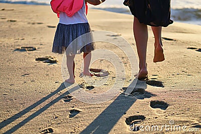 Footprints in sand. Feet of mother and child walk along shore. Summer memories. Stock Photo