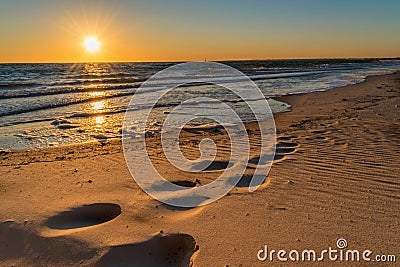 Footprints in the sand at sunset Stock Photo