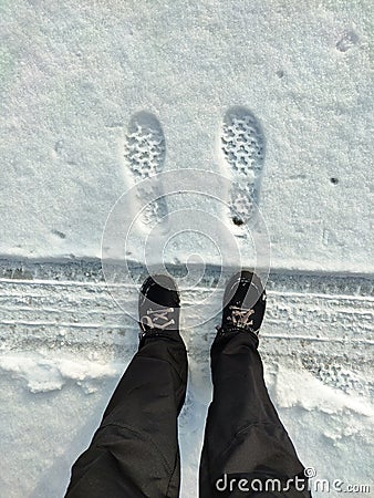 Footprints of shoes on a snow-covered road. A walk in the winter in the snow. Stock Photo