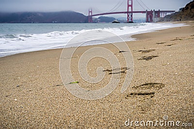 Footsteps on the sand, Golden Gate bridge in the background, California Stock Photo