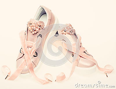 Footwear for girls and women decorated with pearl beads. Femininity concept. Pair of pale pink female sneakers with Stock Photo