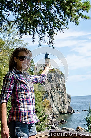 Forced perspective view of a pretty female appearing to be holding lighthouse Stock Photo