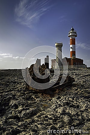 Toston lighthouse Faro de Toston in Fuerteventura with rusty ship wreck in foreground on rocks Stock Photo