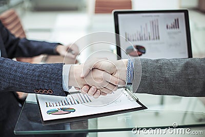 Handshake financial partners on the background of the workplace with financial papers Stock Photo