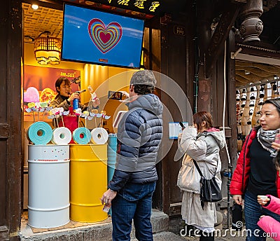 Foreign tourist taking photo of salesgirl making icecream cake with smart phone at Ciqikou Editorial Stock Photo