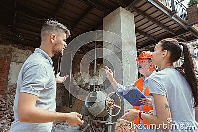 Foreman or achitect shows house, office or store design plans to a young couple Stock Photo