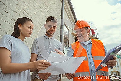 Foreman or achitect shows house, office or store design plans to a young couple Stock Photo