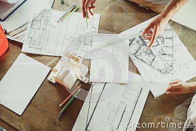 Foreman or achitect shows house, office or store design plans to a young couple Stock Photo