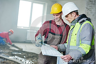 Foreman builder and construction worker with blueprint in indoor apartment Stock Photo