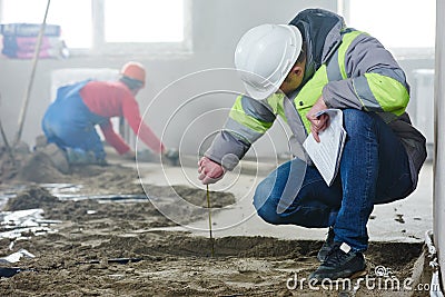 Foreman builder inspecting concrete construction work in apartment Stock Photo