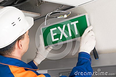 Foreman completes installation of lighting signs emergency exit Stock Photo