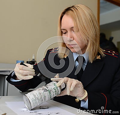 Forensic expert police pulls fingerprints found on the can of the crime scene. Editorial Stock Photo