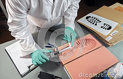 Forensic scientist investigates shoeprint mould evidence in crime lab Stock Photo