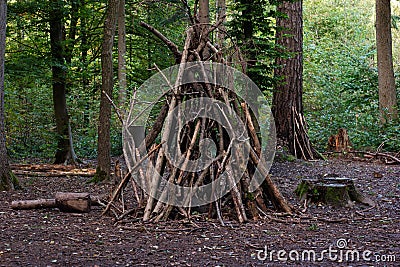 Forest camp site tall wooden tent made of branches autumn day Stock Photo