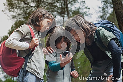 Forest Exploration: Three Children Using a Compass to Navigate and Find Their Way Stock Photo