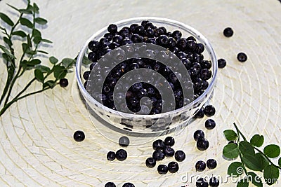 forest Northern berry blueberry lies in a transparent plate on a round light wicker background Stock Photo