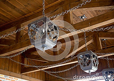 Forged beautiful handmade lampshades for lighting under a wooden ceiling with chains, antique Stock Photo