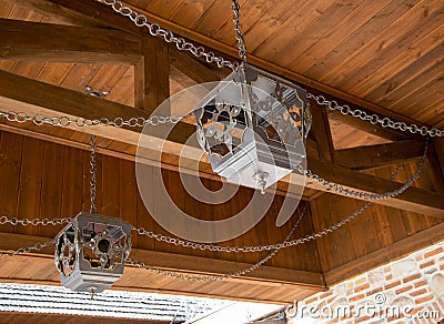 Forged beautiful handmade lampshades for lighting under a wooden ceiling with chains, antique Stock Photo