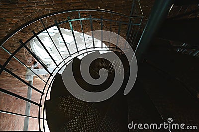 Forged iron twisted stairs with reflection on a red brick wall, handrails of the old vintage building, window with ornament Stock Photo