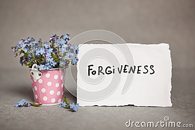 Forgiveness - text on white real paper with blue flowers Stock Photo